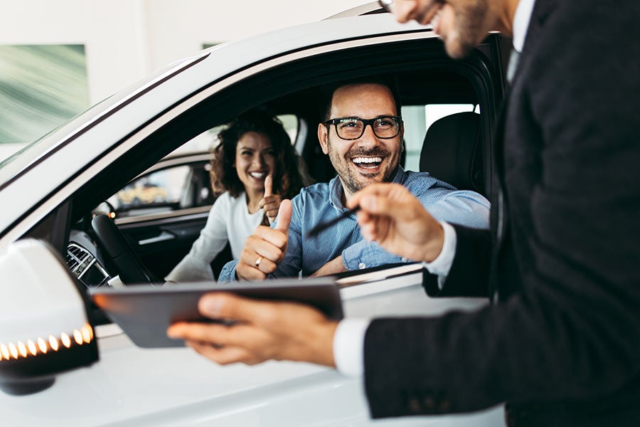 couple in car signing with salesman