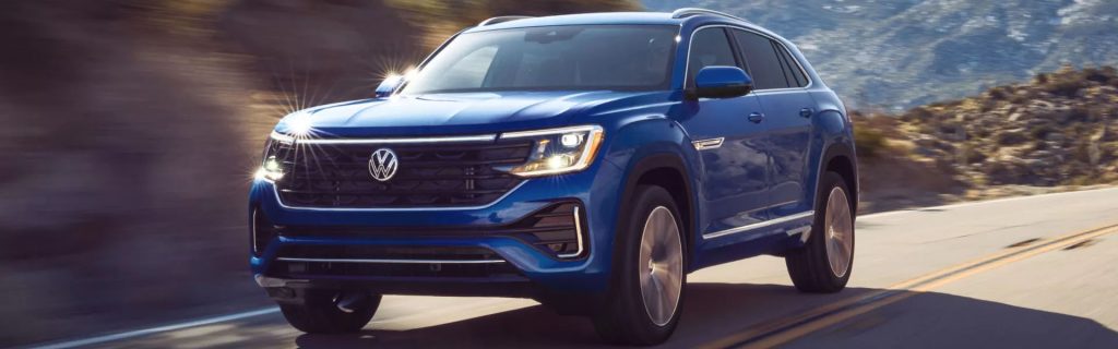 Blue 2026 VW Atlas Cross Sport SUV on a road, front three-quarter view